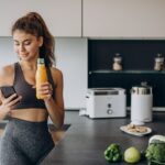 Mujer deportiva en la cocina a través de teléfono móvil
